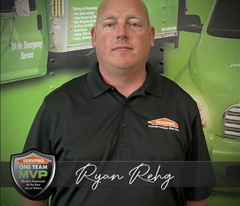 A SERVPRO Employee in front of a SERVPRO themed graphic on trailer