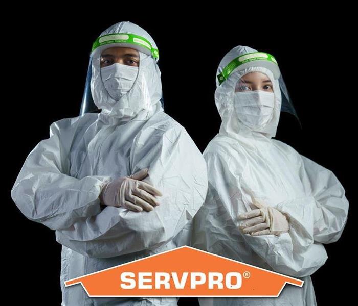 a man and woman in full personal protective equipment with a SERVPRO logo